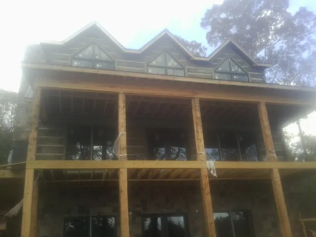 Dormers and porch framing on a large log home under construction — Roof Coating work by our crew in Battle Lake