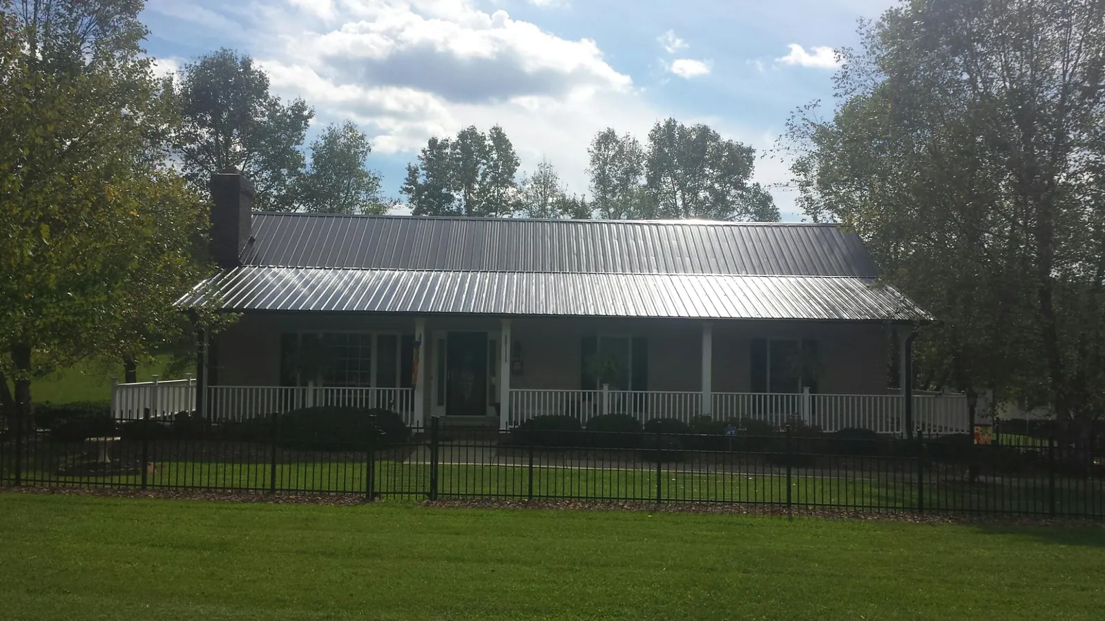 Gray metal roof on a brick ranch with a full width front porch — Gutter Guard Installation work by our crew in Battle Lake