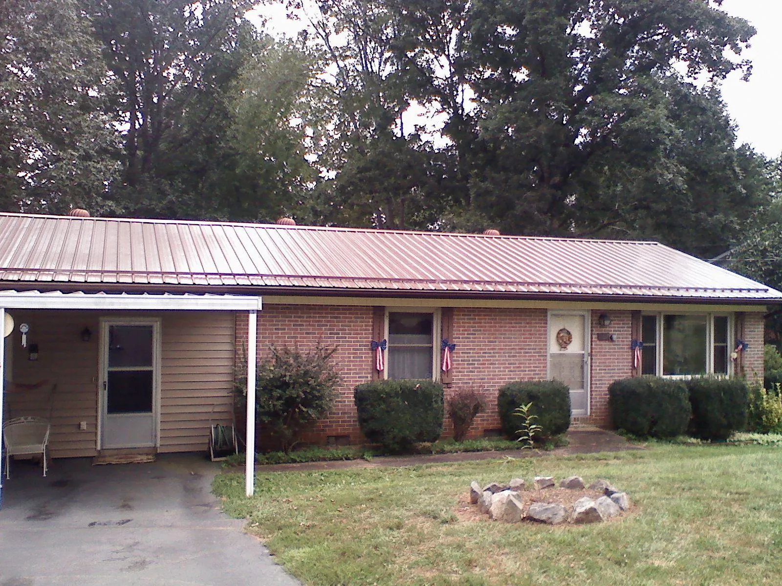 Bronze metal roof and carport on a brick ranch home — Roof Repair work by our crew in Battle Lake