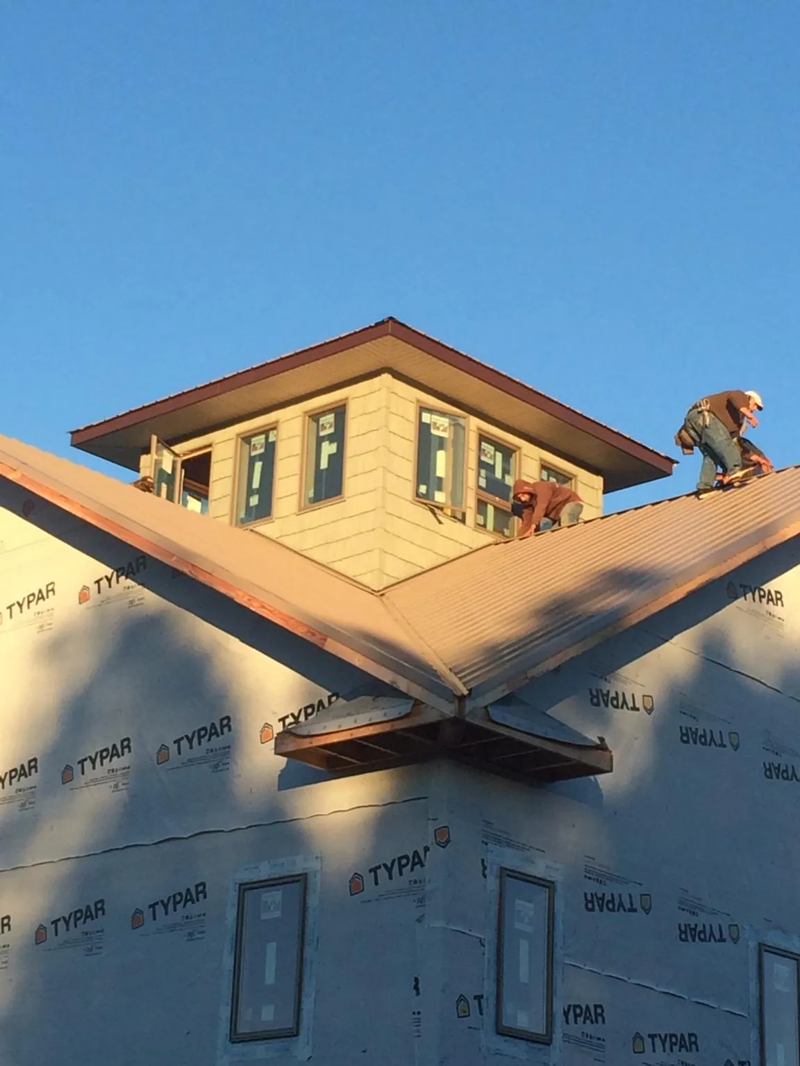Roofers working around a rooftop cupola on a new metal roof at sunset — Roof Waterproofing in Battle Lake by Roofing Brothers